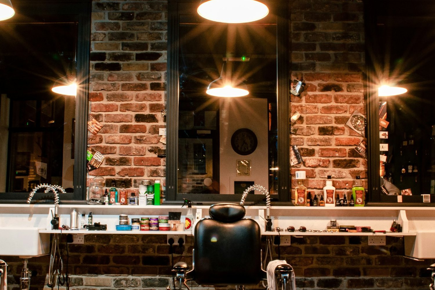 The row of barber's chairs and the mirrors along the brick wall, under the shop's pendant lamps