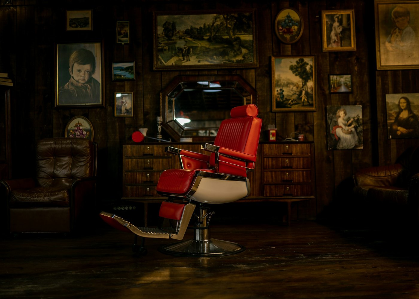 The red chair in the back room, the wall behind it hung with framed pictures